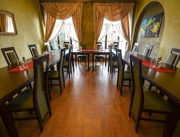 Un comedor con una mesa larga, sillas y cortinas.