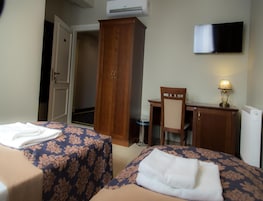 Habitación de hotel con dos camas, un escritorio, una silla, un televisor y un armario.
