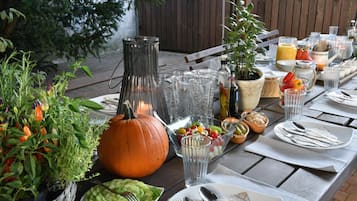 An outdoor dining table set with various dishes, a pumpkin centerpiece, and a bottle of olive oil.