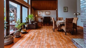 Una habitación con un piano, muebles de mimbre y plantas en macetas.