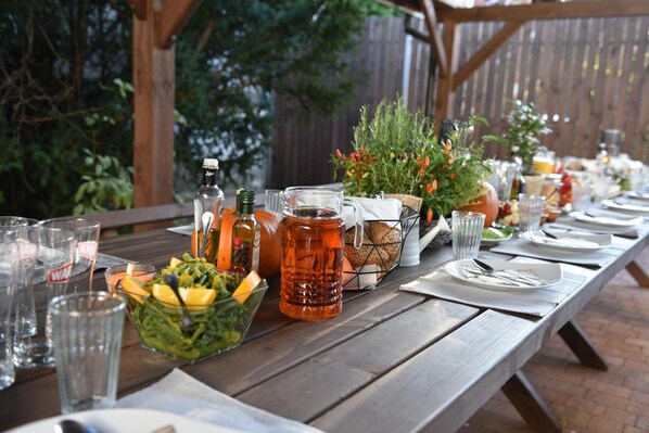 A wooden table set for a meal with clear glasses, a pitcher, and a bowl of salad.
