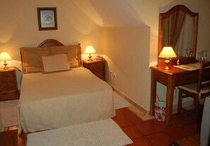 A bedroom with a bed, two bedside tables with lamps, a wooden chair, a desk, and a mirror. - Jardim (Elvas)