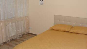 A bedroom with a bed, a no smoking sign, and a window with sheer curtains.
