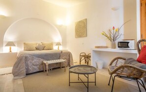 A bedroom with a bed, bedside tables, a small table, and wicker chairs.