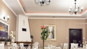 A dining room with a large table set for six, a chandelier, and a painting on the wall.