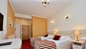 A hotel room with two beds, a desk, and a chair.