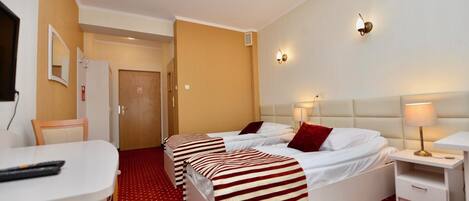 A hotel room with two beds, a desk, and a chair.