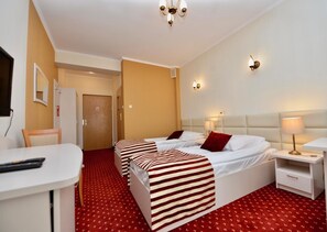 A hotel room with two beds, a desk, and a chair.