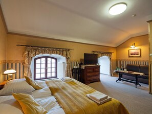 A hotel room with a large bed, a desk, a chair, and a television.