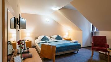 A hotel room with a bed, bedside tables, a desk, a chair, and a TV.