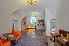 A hotel lobby with a brick fireplace, a glass display case, and a seating area with orange chairs.