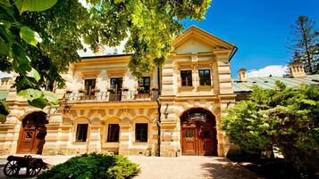 A historic building with a symmetrical facade, large wooden doors, and a balcony with flower boxes.