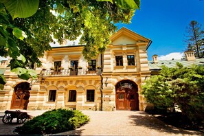 A historic building with a symmetrical facade, large wooden doors, and a balcony with flower boxes.