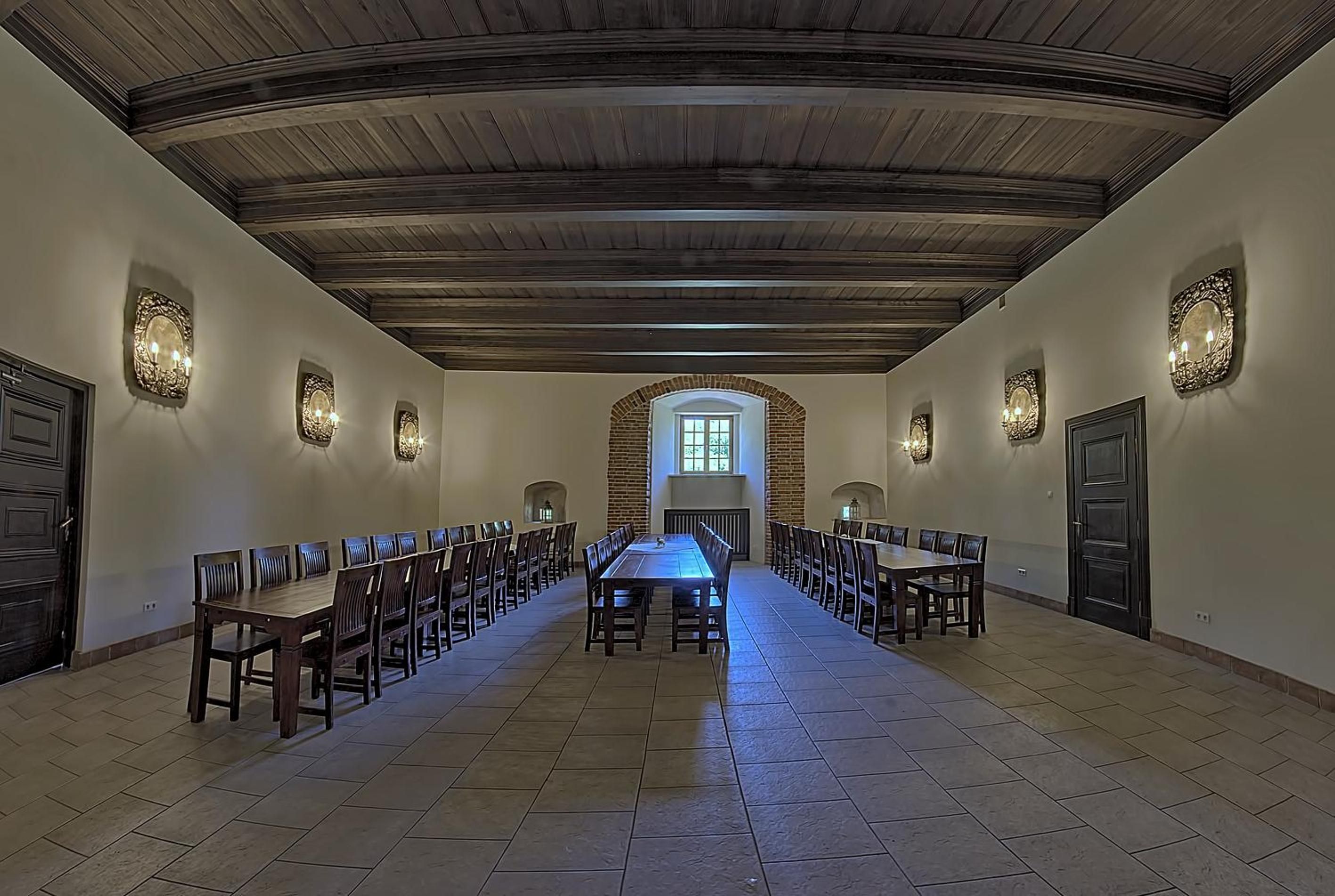 A long dining hall with high ceilings and arched windows.