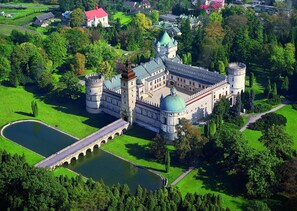 A castle with a moat, a bridge, and a large green lawn.