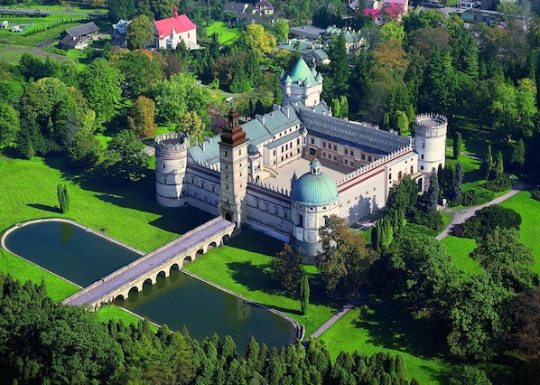 A castle with a moat, a bridge, and a large green lawn.