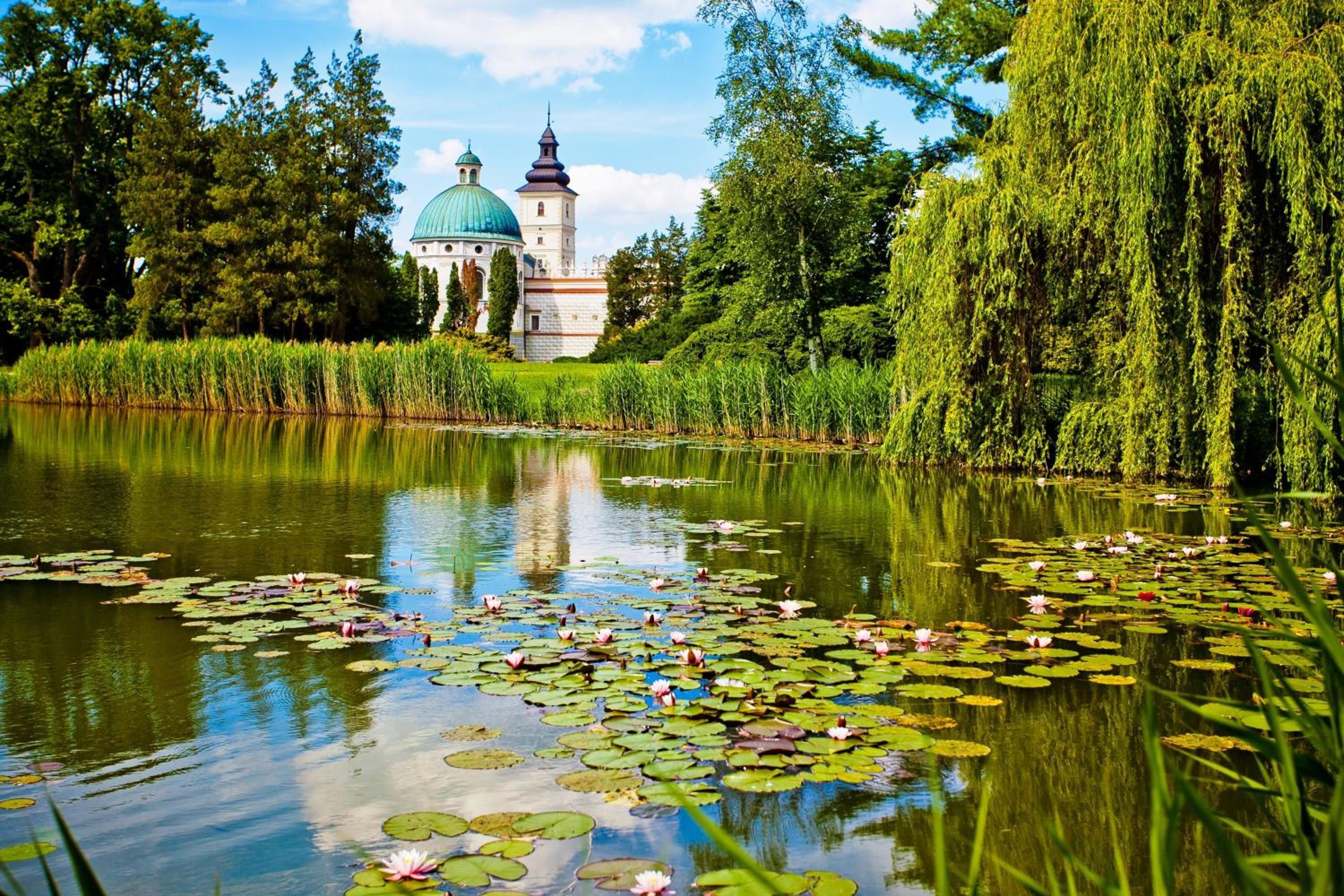 A serene pond with lily pads and a building with domed architecture in the background.
