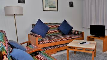 A living room with a sofa, armchair, and a small table with a remote control.