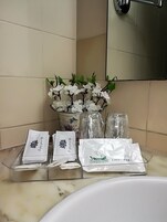 A bathroom vanity with a white sink, a mirror, and a decorative arrangement of white flowers and green leaves.
