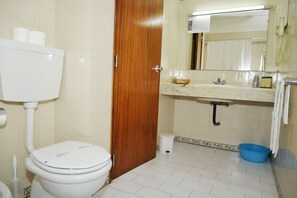 A bathroom with a toilet, sink, mirror, and a blue basin. - Apartamentos Lindomar (Silves)