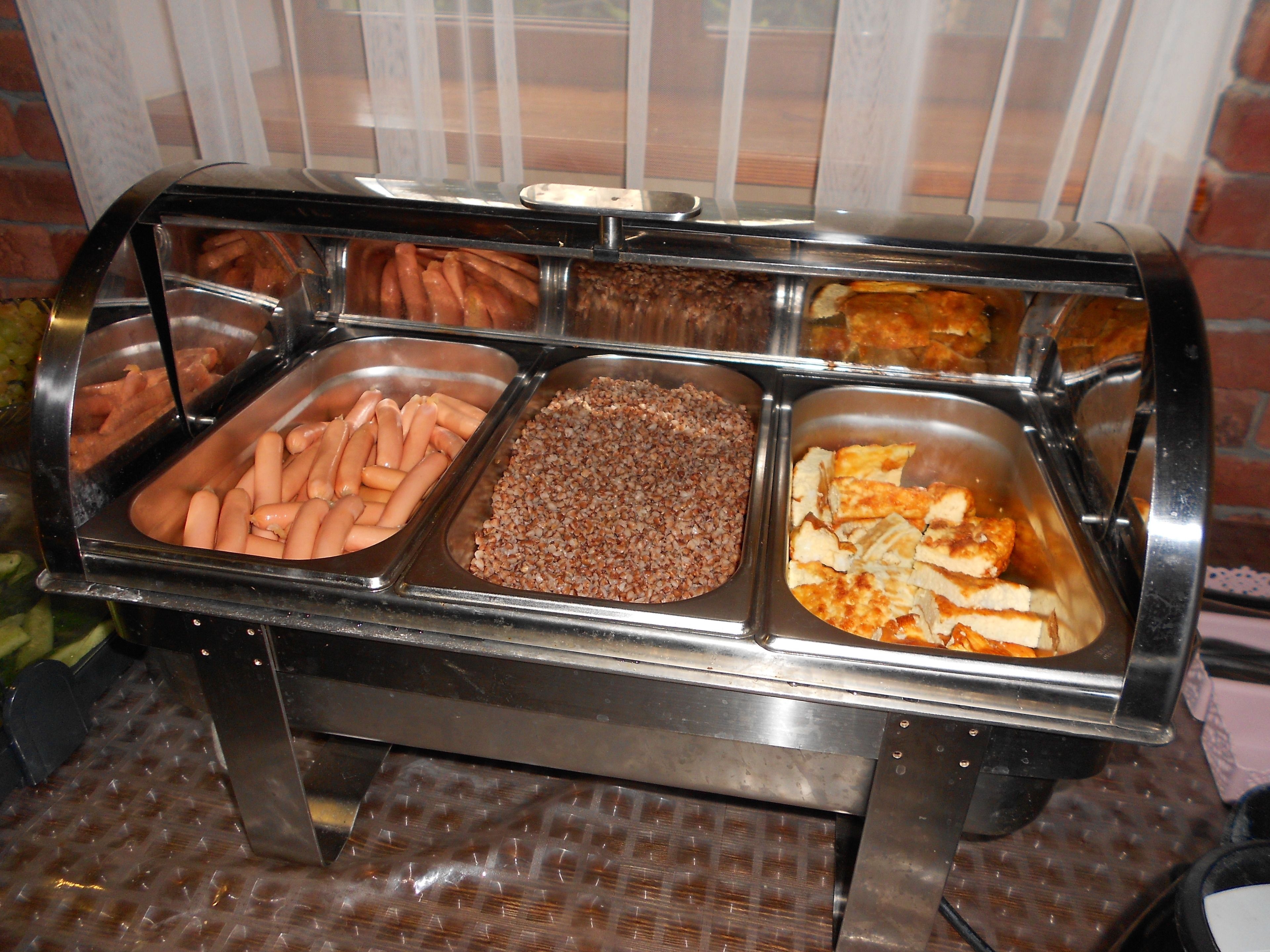 Un bufé con diversas opciones de comida, como perros calientes, un plato de cereales y un pastel de horno.