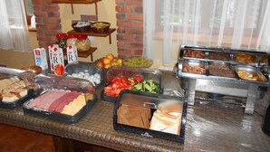 Un bufé con diversos alimentos, incluyendo carnes, quesos, frutas y verduras.