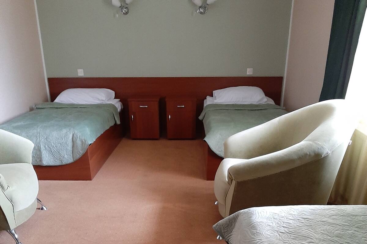A hotel room with two single beds, a sofa, and a small cabinet.