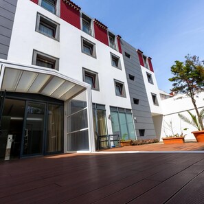 Un edifici modern amb teulada plana, grans finestres i entrada coberta.