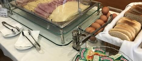 Un bufé con embutidos, huevos y pan.