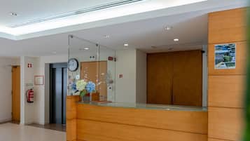 A reception area with a wooden reception desk, a clock, and a fire extinguisher on the wall.