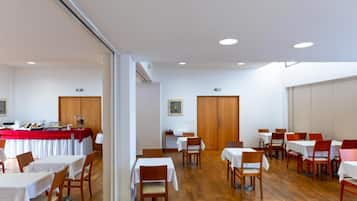 A dining area with tables and chairs, a buffet setup, and a wooden floor.