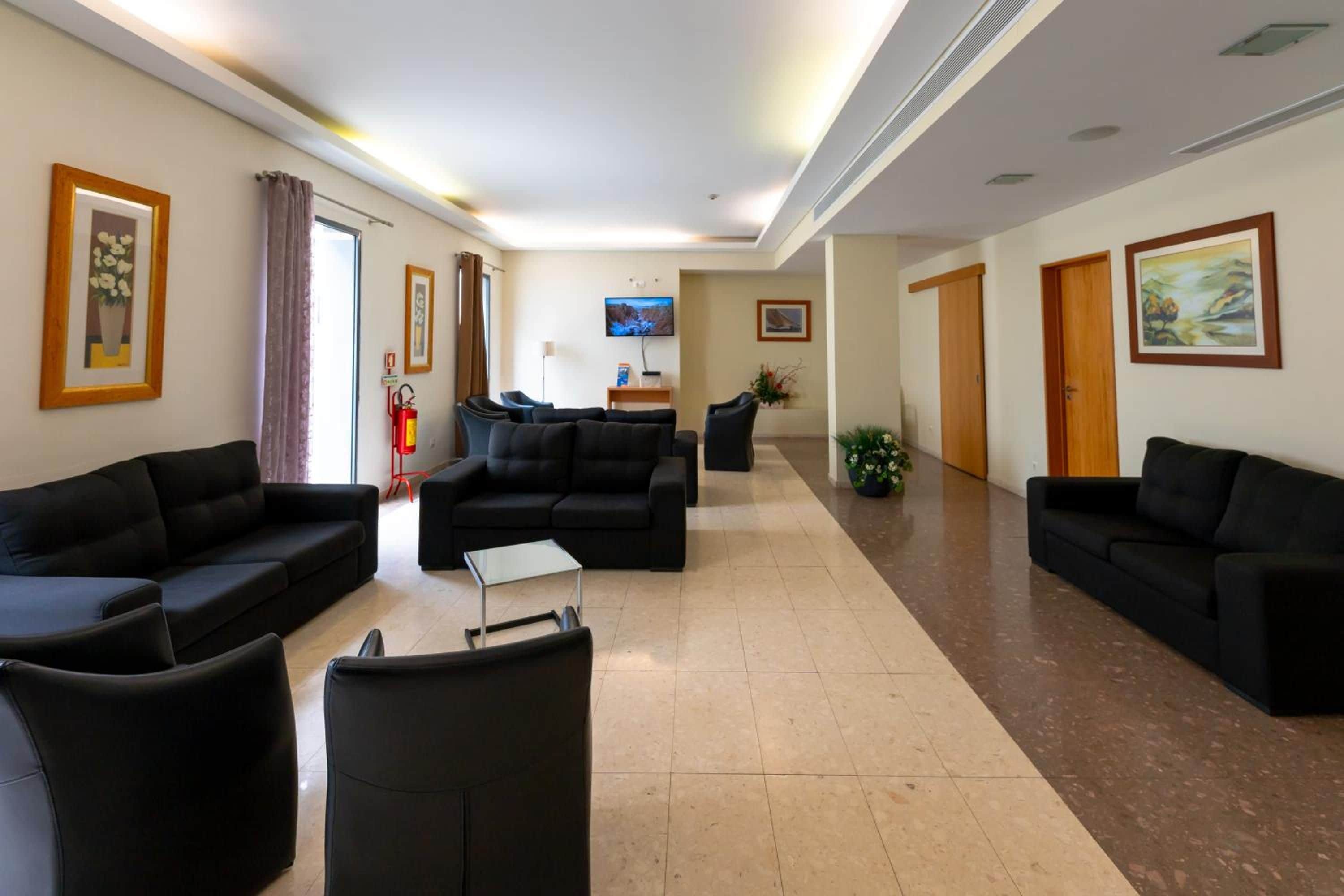 A hotel lobby with black sofas, a flat-screen TV, and artwork on the walls.