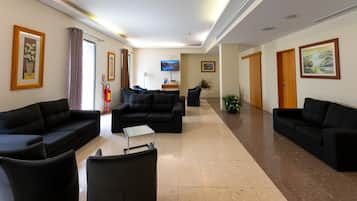 A hotel lobby with black sofas, a flat-screen TV, and artwork on the walls.