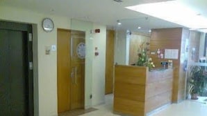 A reception area with a wooden reception desk, a clock on the wall, and a door leading to another room. - Matriz (Ponta Delgada)