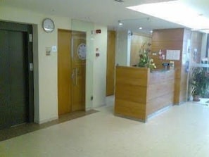 A reception area with a wooden reception desk, a clock on the wall, and a door leading to another room. - Matriz (Ponta Delgada)