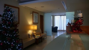 A hotel lobby with a Christmas tree, a sofa, a coffee table, and a dining table with candles. - Matriz (Ponta Delgada)