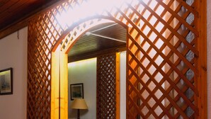 A wooden lattice doorway leading to a room with a tiled floor and a wicker chair. - Casa Do Jardim (Ponta Delgada)