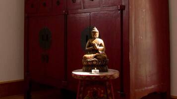 Et træskab med blomstermotiver og en Buddha-figur på et lille bord.