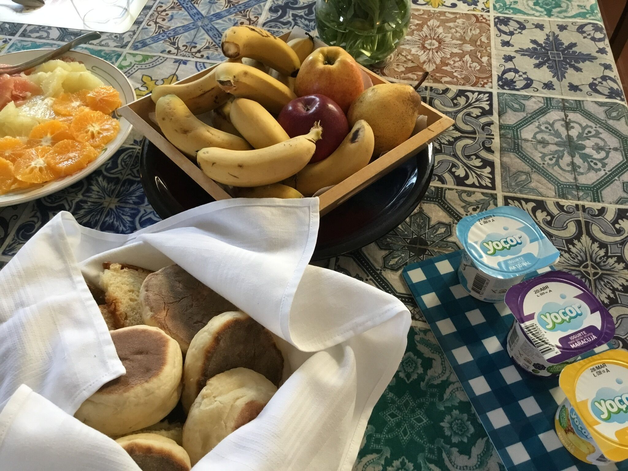 A table with a variety of food items including fruits, bread, and yogurt containers.