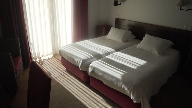 Une chambre d’hôtel avec deux lits, une table de chevet, une lampe et une chaise.