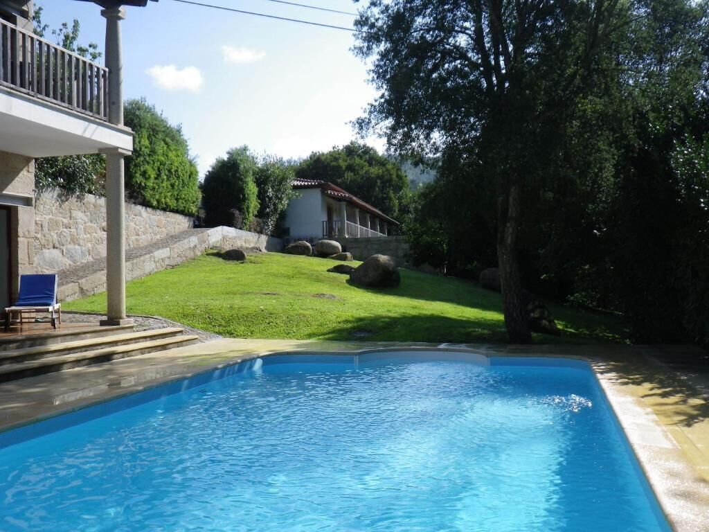 A swimming pool with a stone wall and a grassy area.
