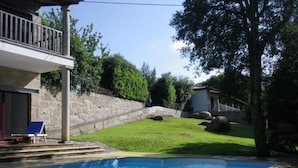 Une piscine avec un mur en pierre et une zone herbeuse.