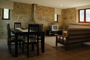 Uma área de refeições com parede de pedra, uma televisão e um sofá.