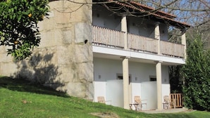 Un bâtiment en pierre doté d’un balcon, d’une pelouse et d’un arbre.