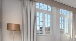 A room with large windows, a floor lamp, and curtains.
