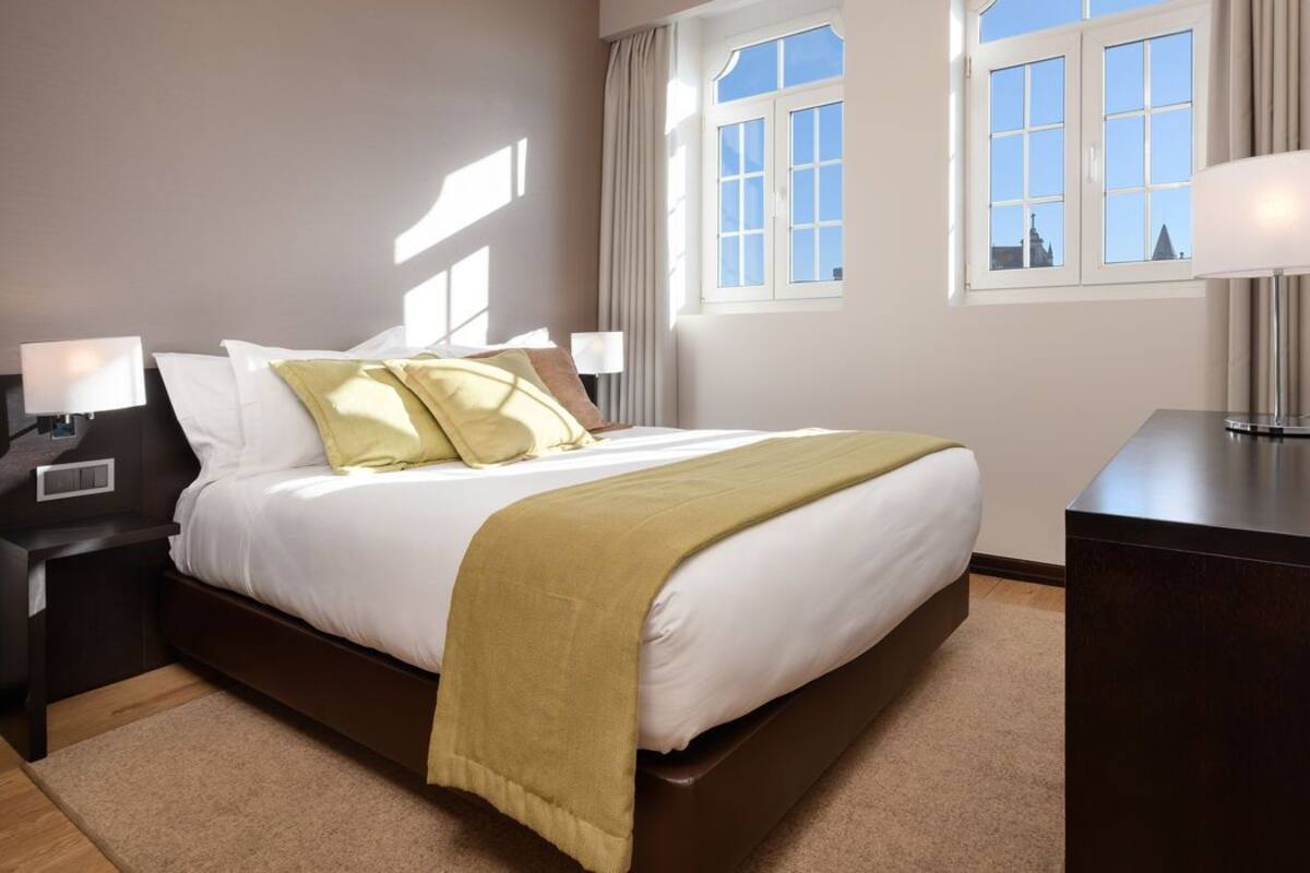 Ein Hotelzimmer mit einem Bett, Nachttischen, einem Schreibtisch und einem Fenster mit Vorhängen.