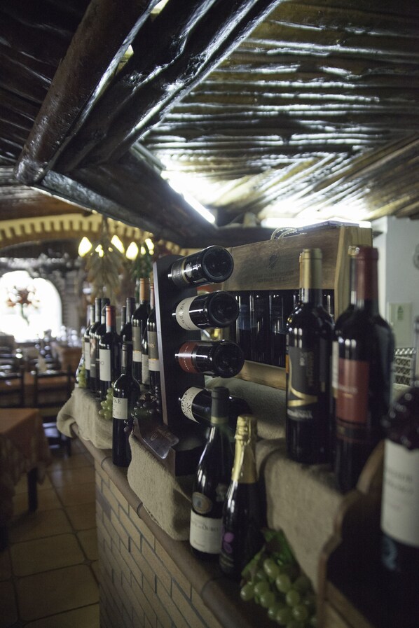 A wine rack with various bottles, a brick wall, and a wooden counter.