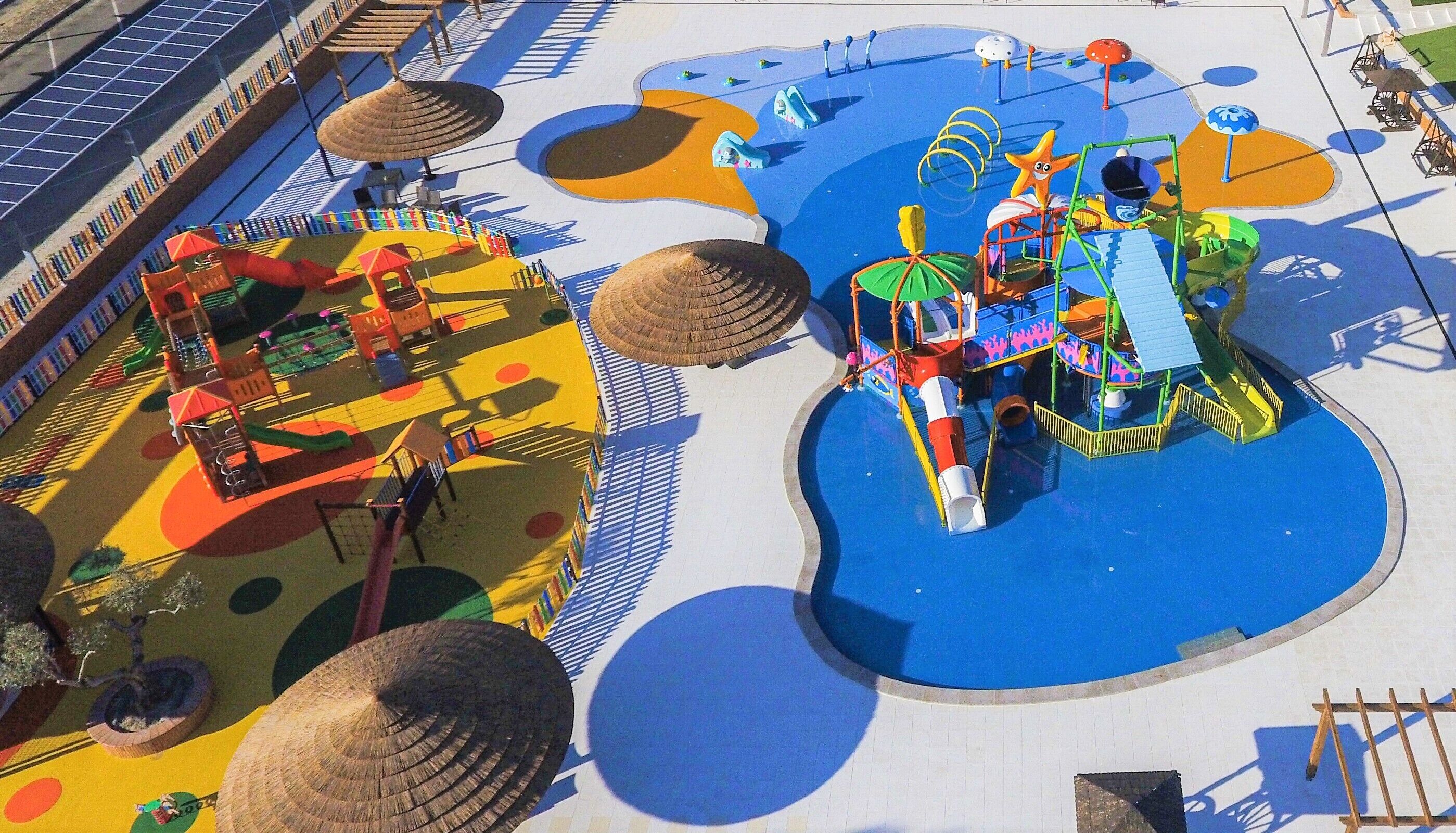 Uma área de recreação infantil com escorregadores, estruturas de escalada e uma piscina.
