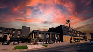 A modern hotel with a flat roof, large windows, and a parking lot. -  Alambique Hotel Resort & Spa  (Fundao)