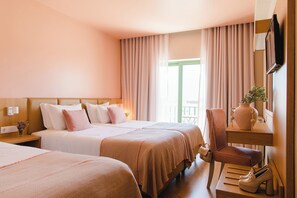 Habitación de hotel con dos camas, una silla, una mesita y un televisor montado en la pared.